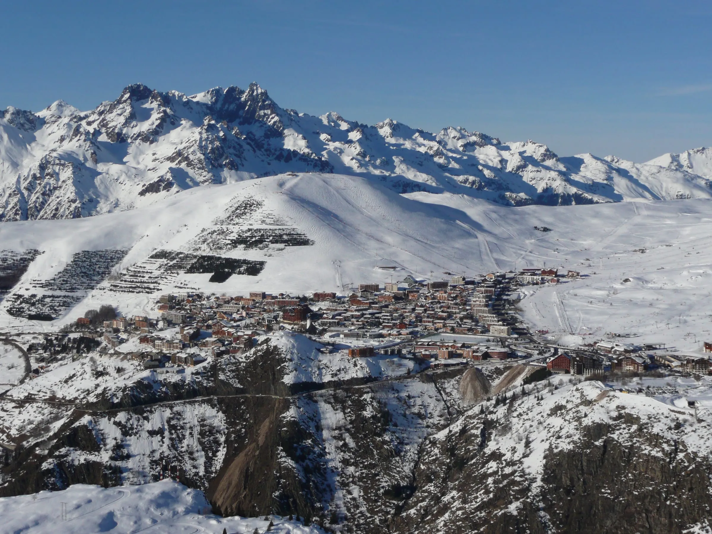 Alpe d'Huez and its ski slopes in winter, with the Belledonne range behind