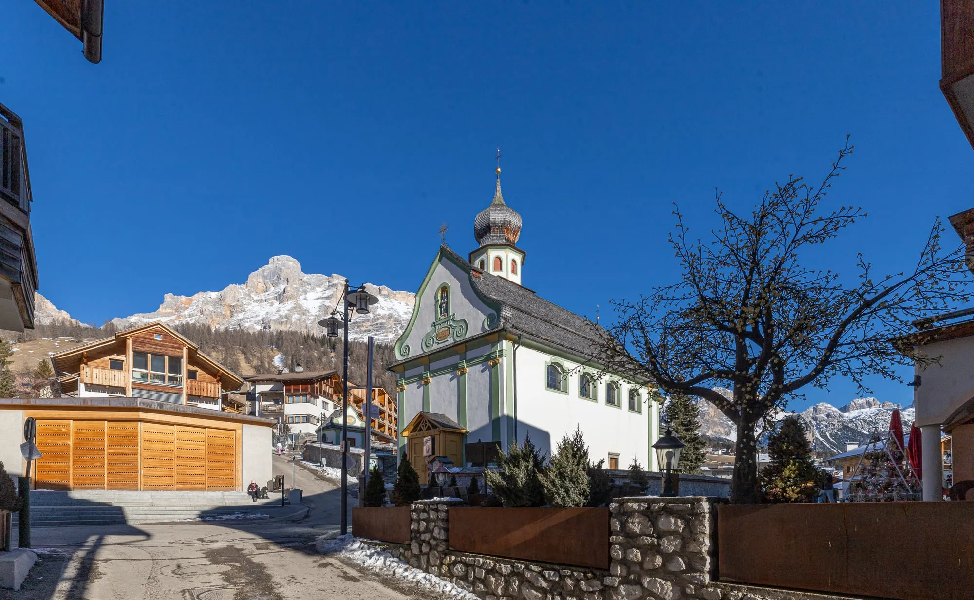 The church and centre of San Cassiano in Alta Badia, with snow-capped Dolomite peaks behind