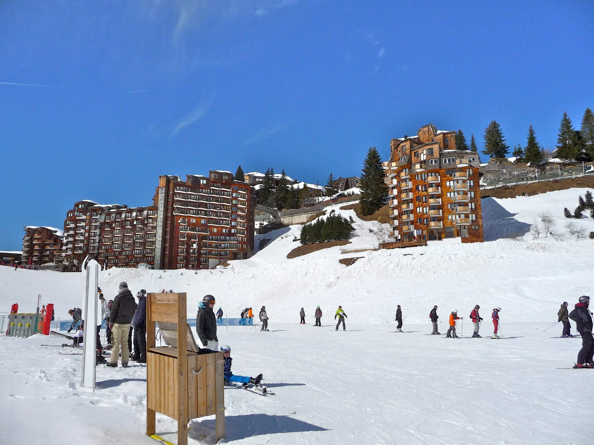 Skiers on a gentle snowy slope below Avoriaz apartment buildings
