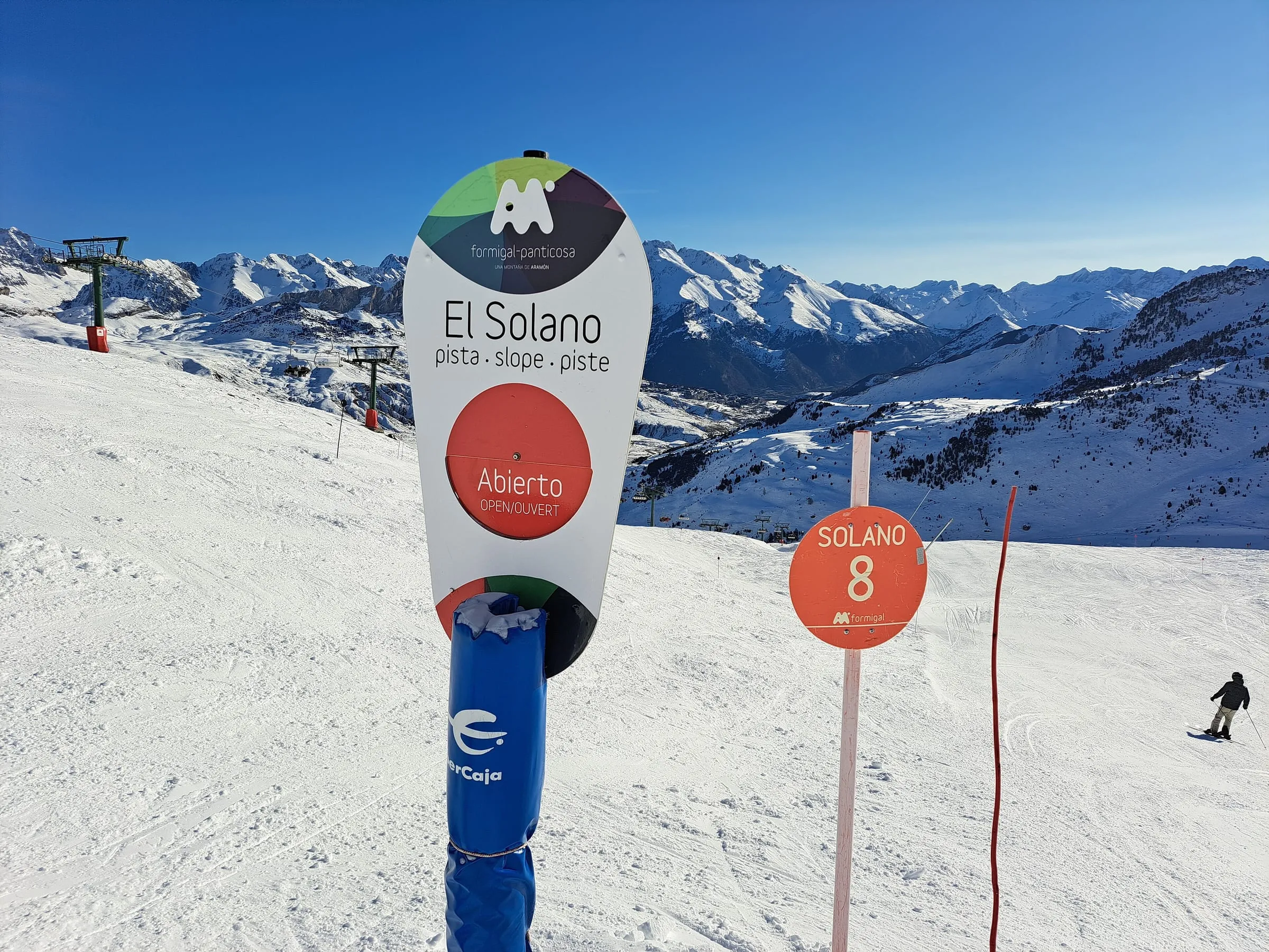 The El Solano piste sign in Formigal with skiers and snowy mountains behind