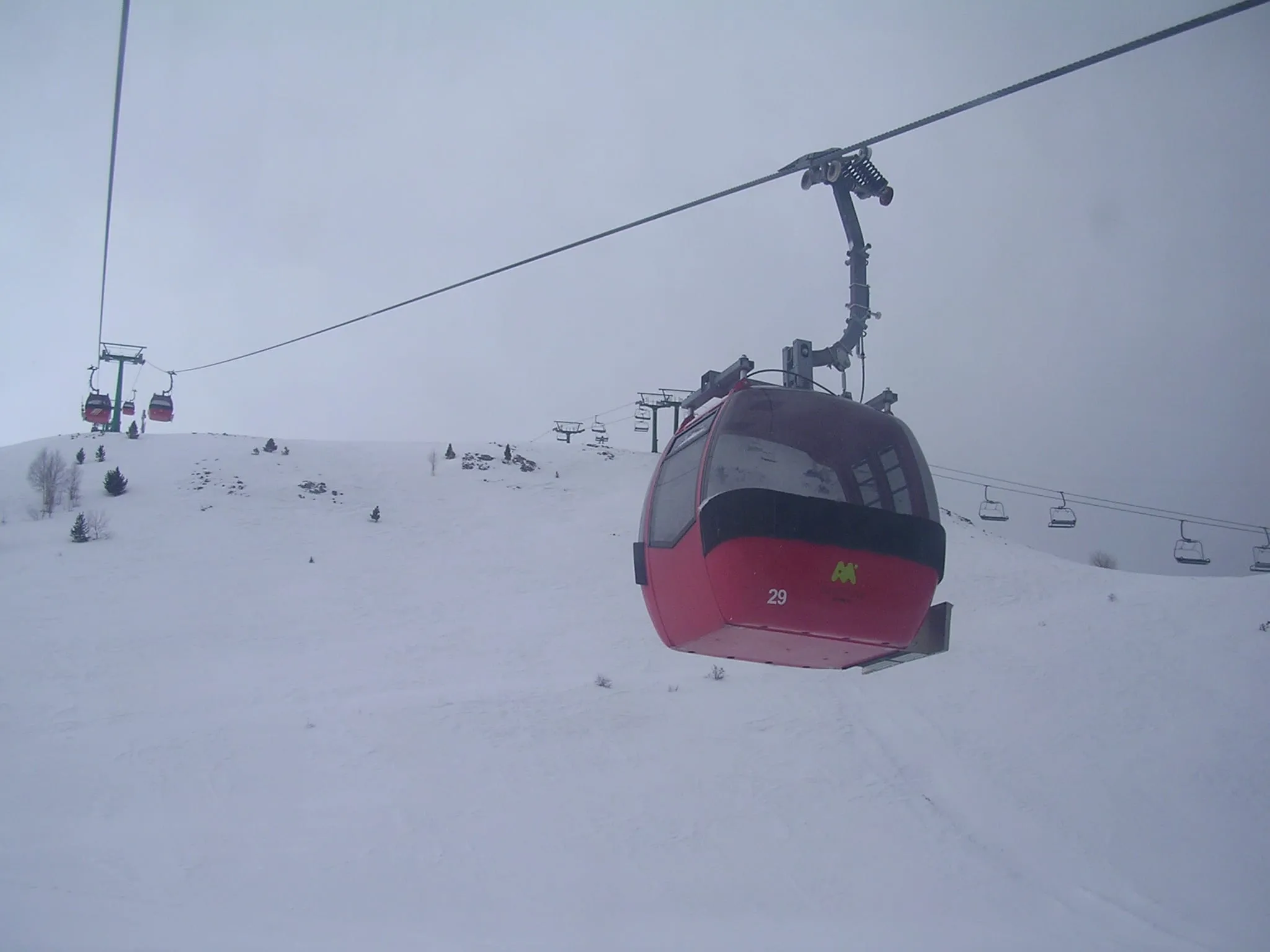 A red gondola cabin on the Panticosa gondola above snowy slopes