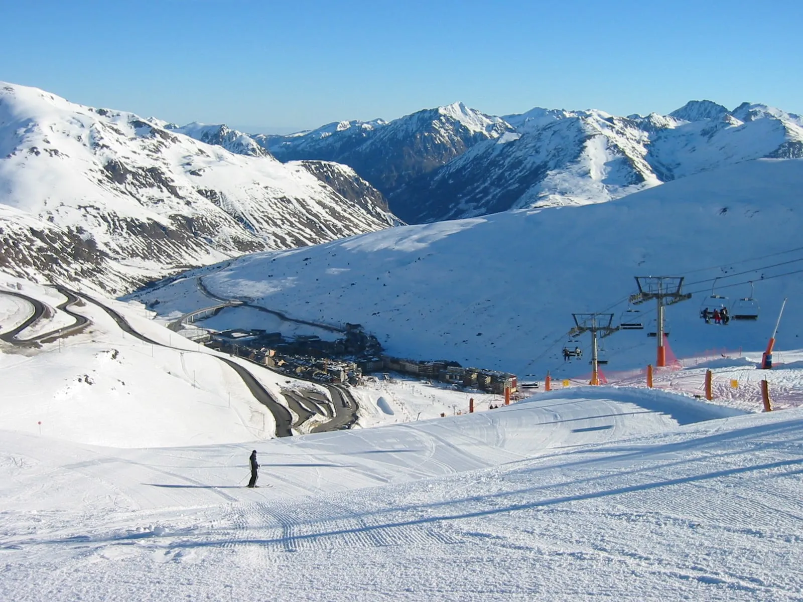 Pas de la Casa and its ski slopes seen from the top of a piste, with chairlifts below