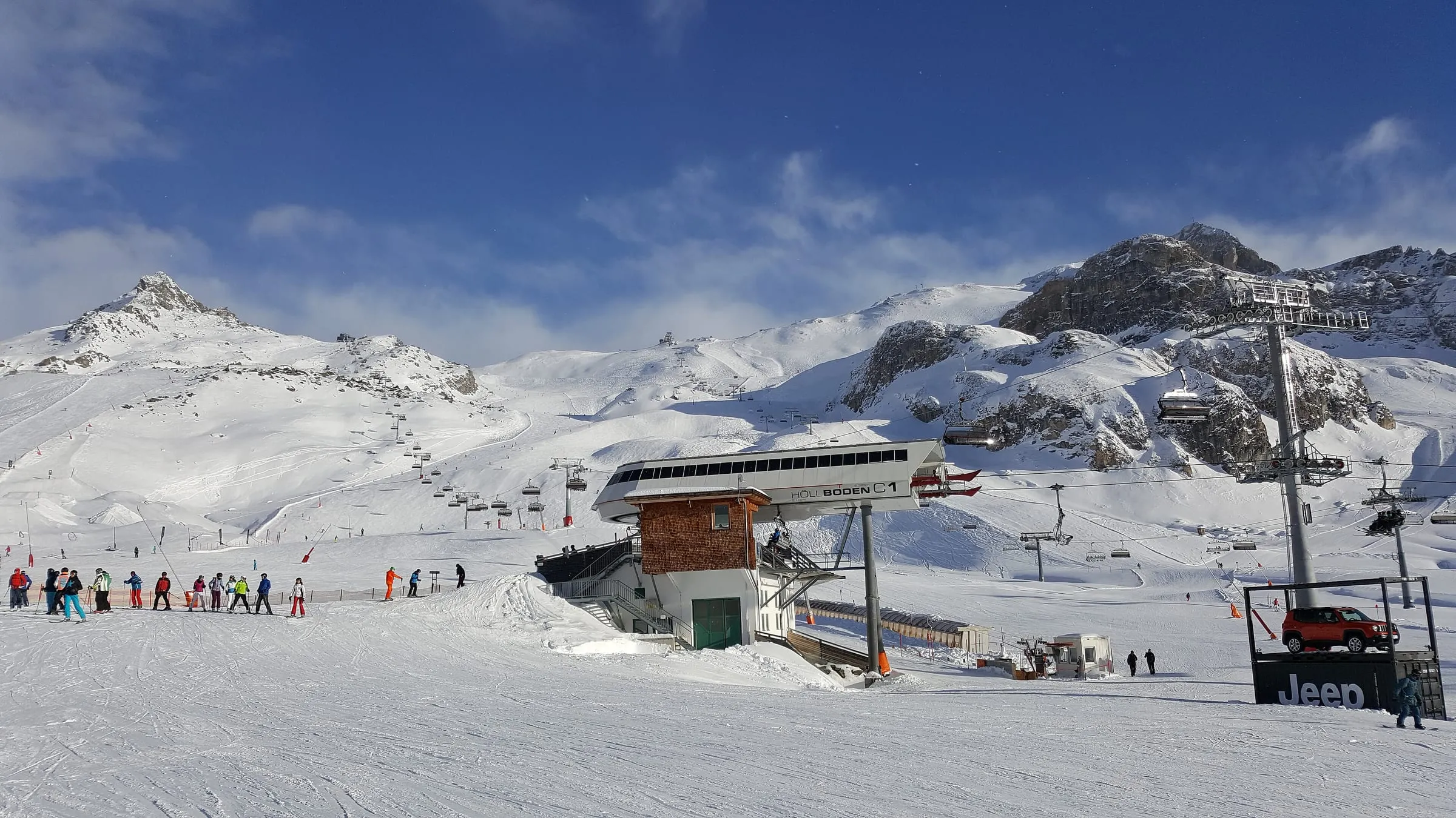 A lift station and skiers on a sunny piste in the Ischgl ski area