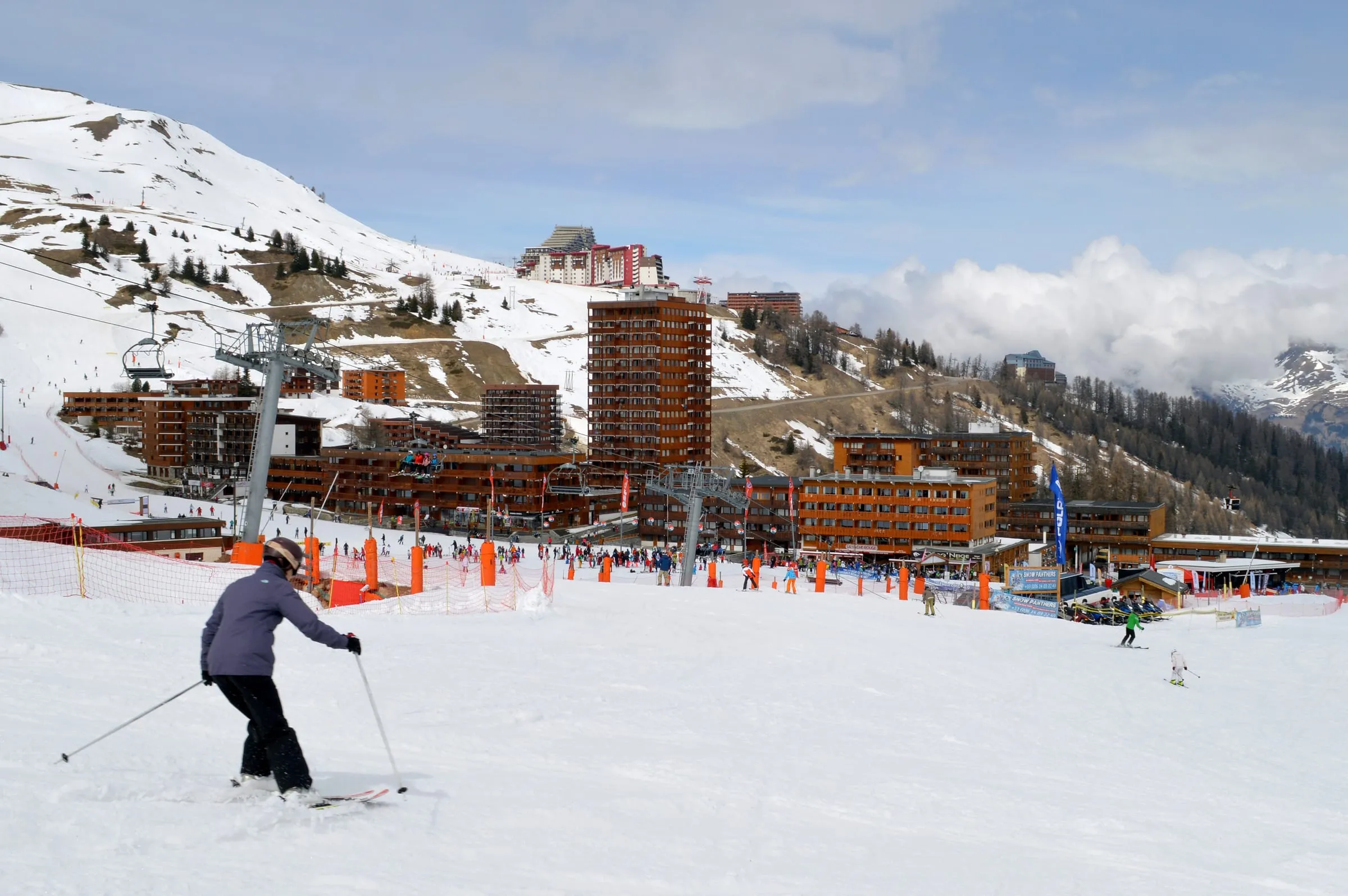 A skier on the snow front at Plagne Centre, with Plagne Aime 2000 on the slope behind