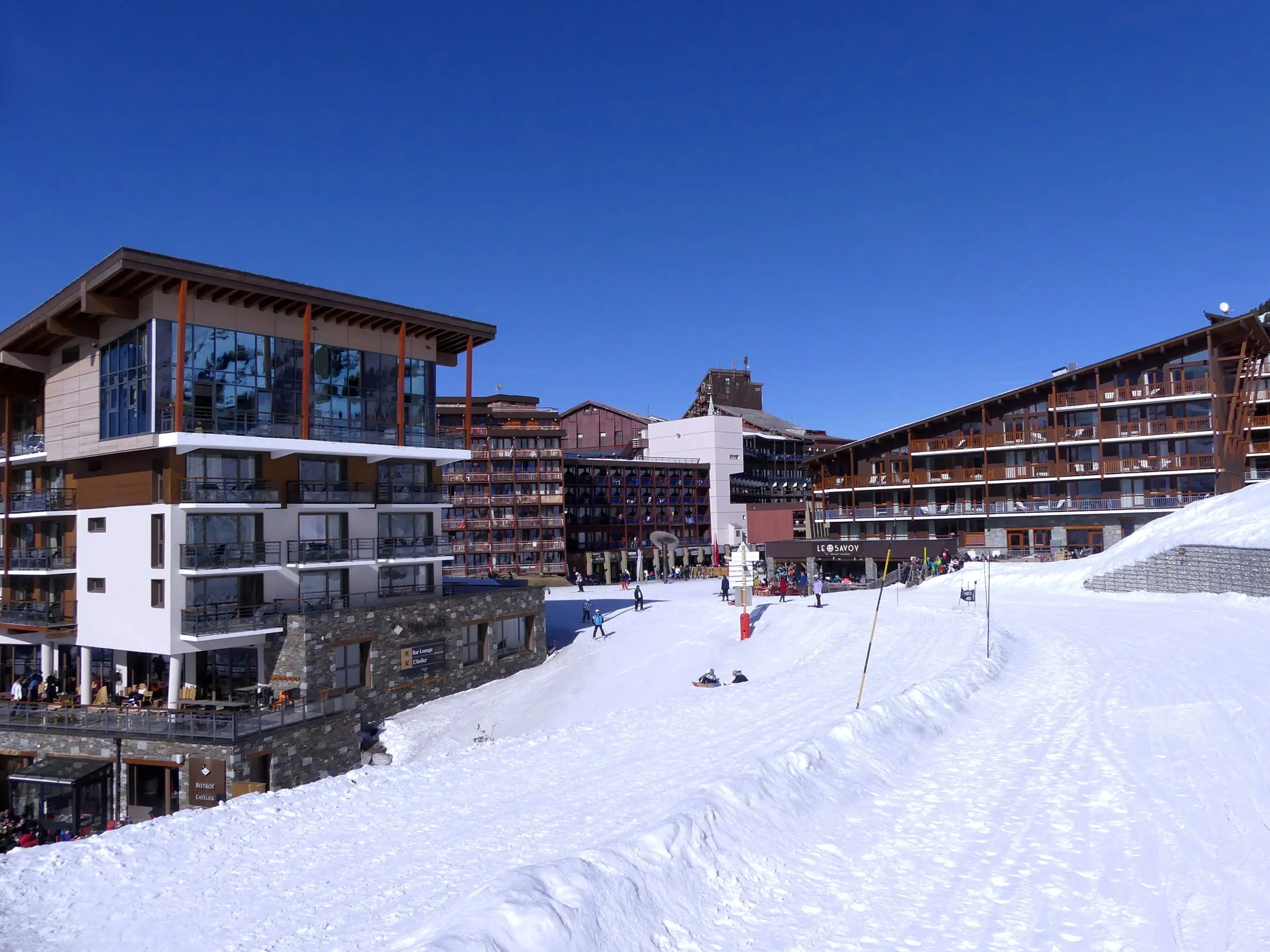 A ski slope leading into the Arc 2000 village, with hotel buildings in the snow