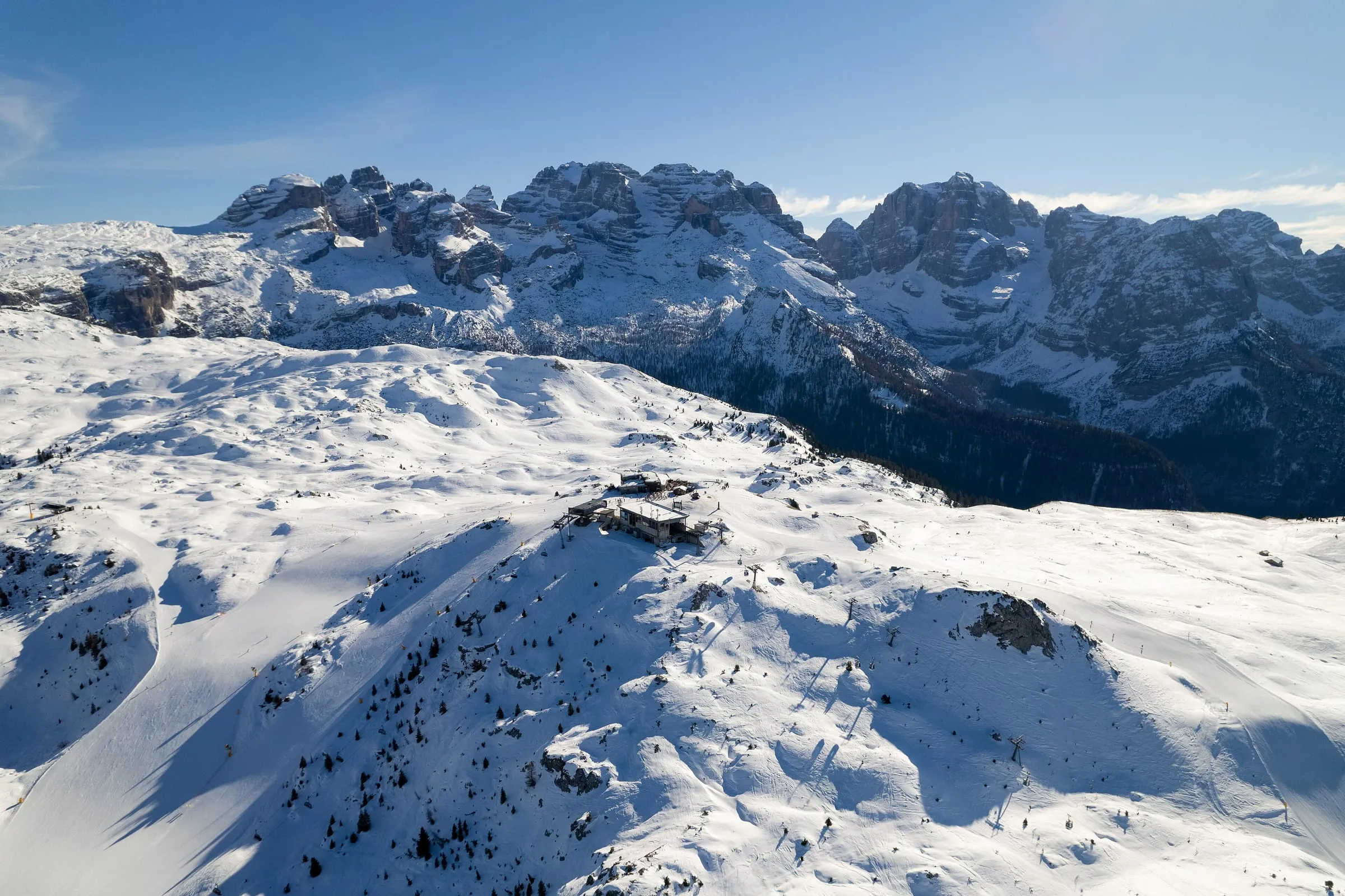 Snowy pistes in the Madonna di Campiglio ski area with the peaks of the Brenta Dolomites behind