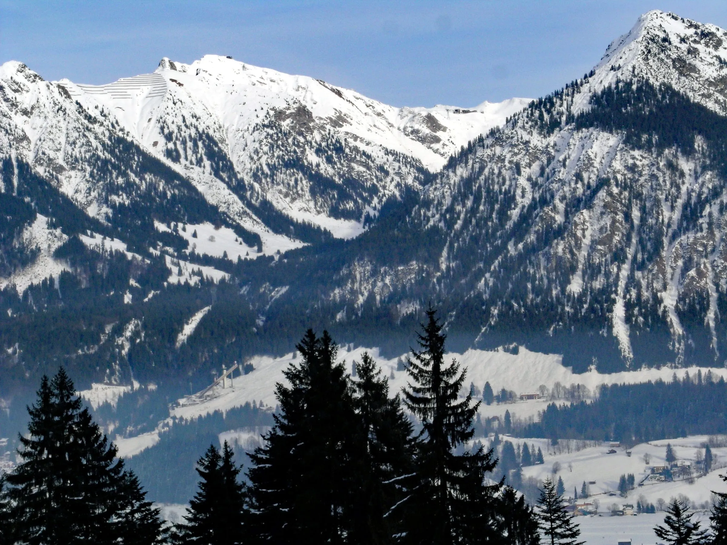 The snowy Nebelhorn above the Oberstdorf valley in winter, with the Schattenberg ski jumps at its foot