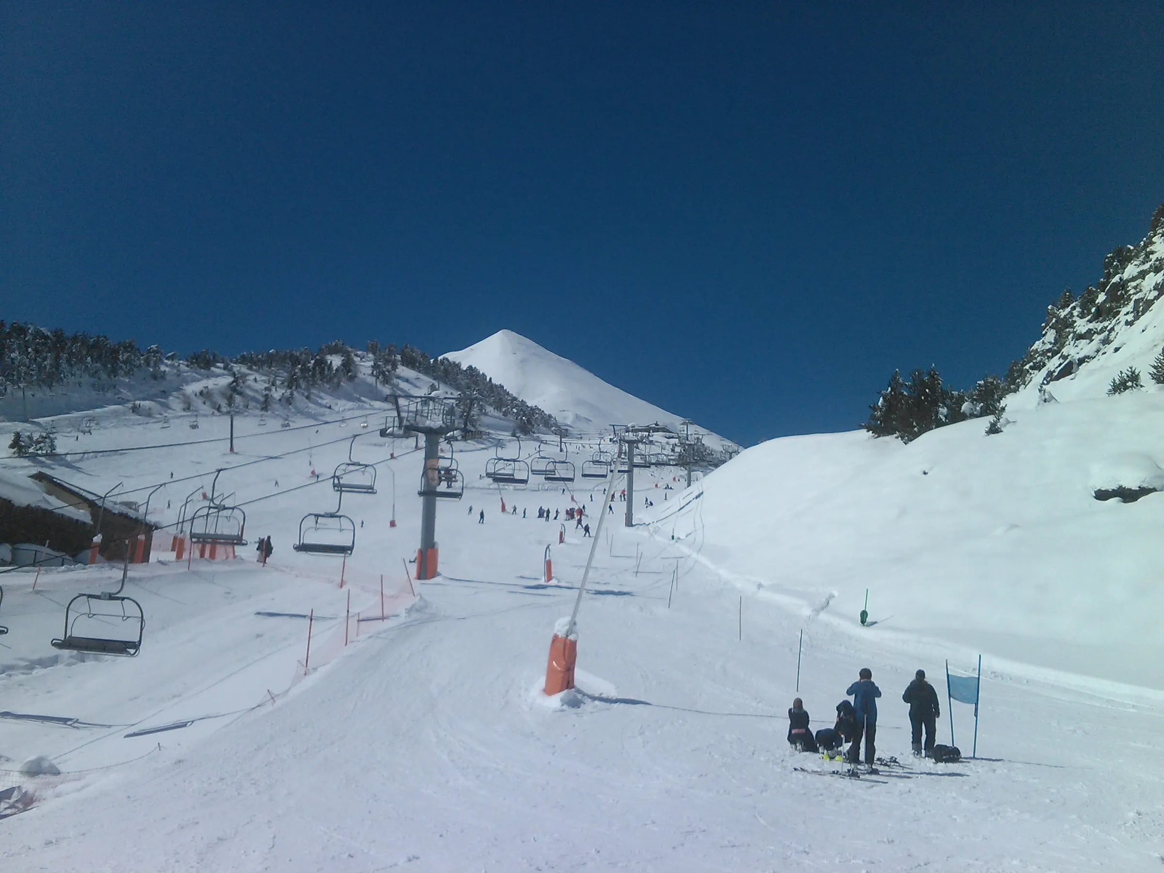 Skiers and chairlifts on the slopes of the Arinsal sector under a blue sky