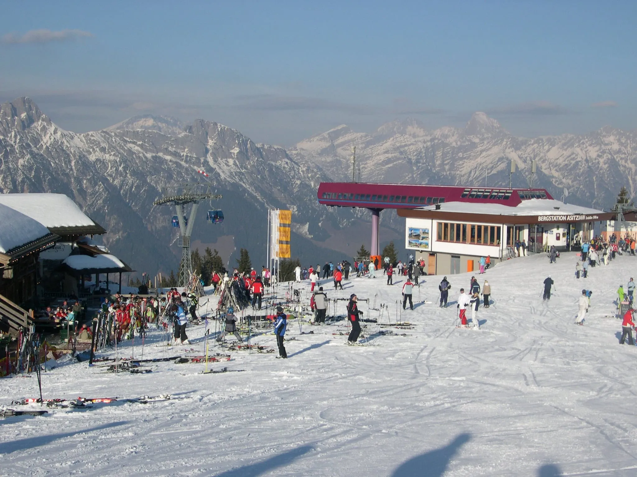Skiers outside the Asitzbahn top station above Leogang in winter, with the Leoganger Steinberge behind