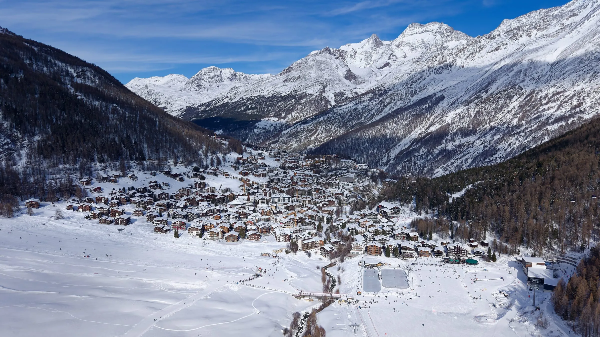 Saas-Fee village and its nursery slopes in winter, with the Saas valley peaks behind