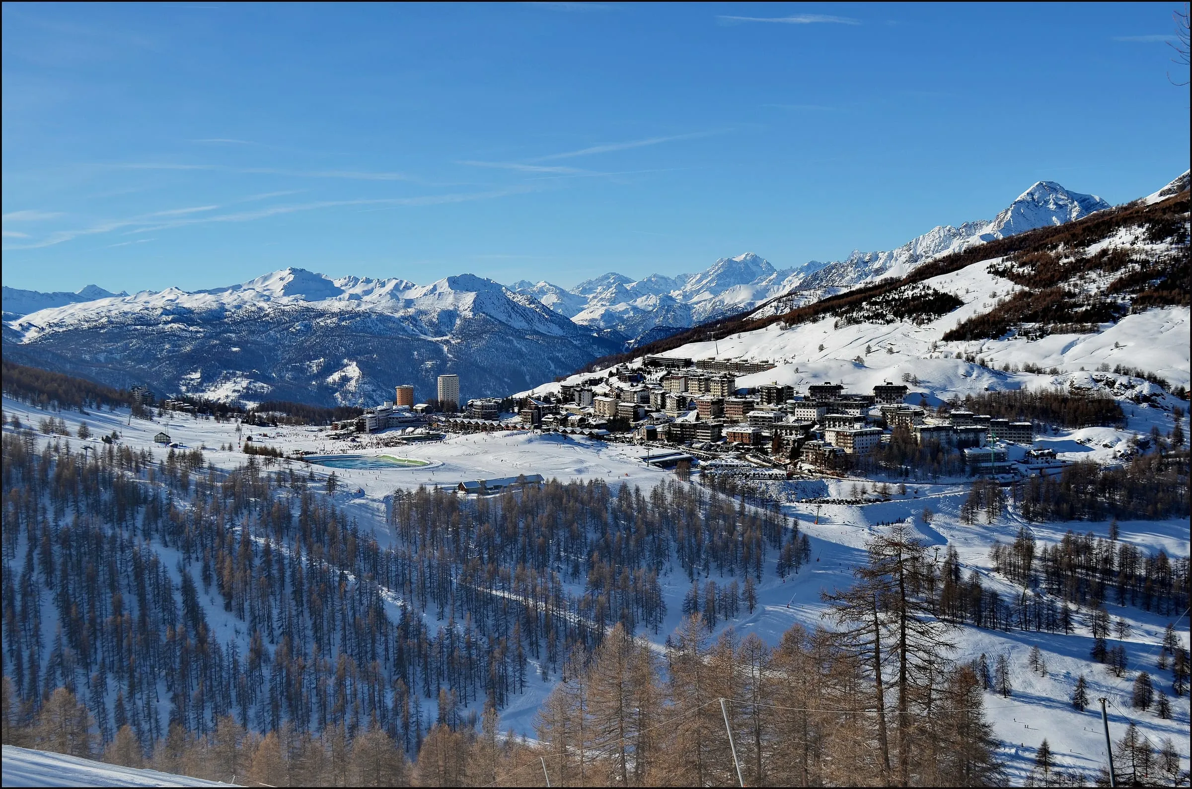Sestriere village on its high pass in winter, with snowy slopes and the Alps behind