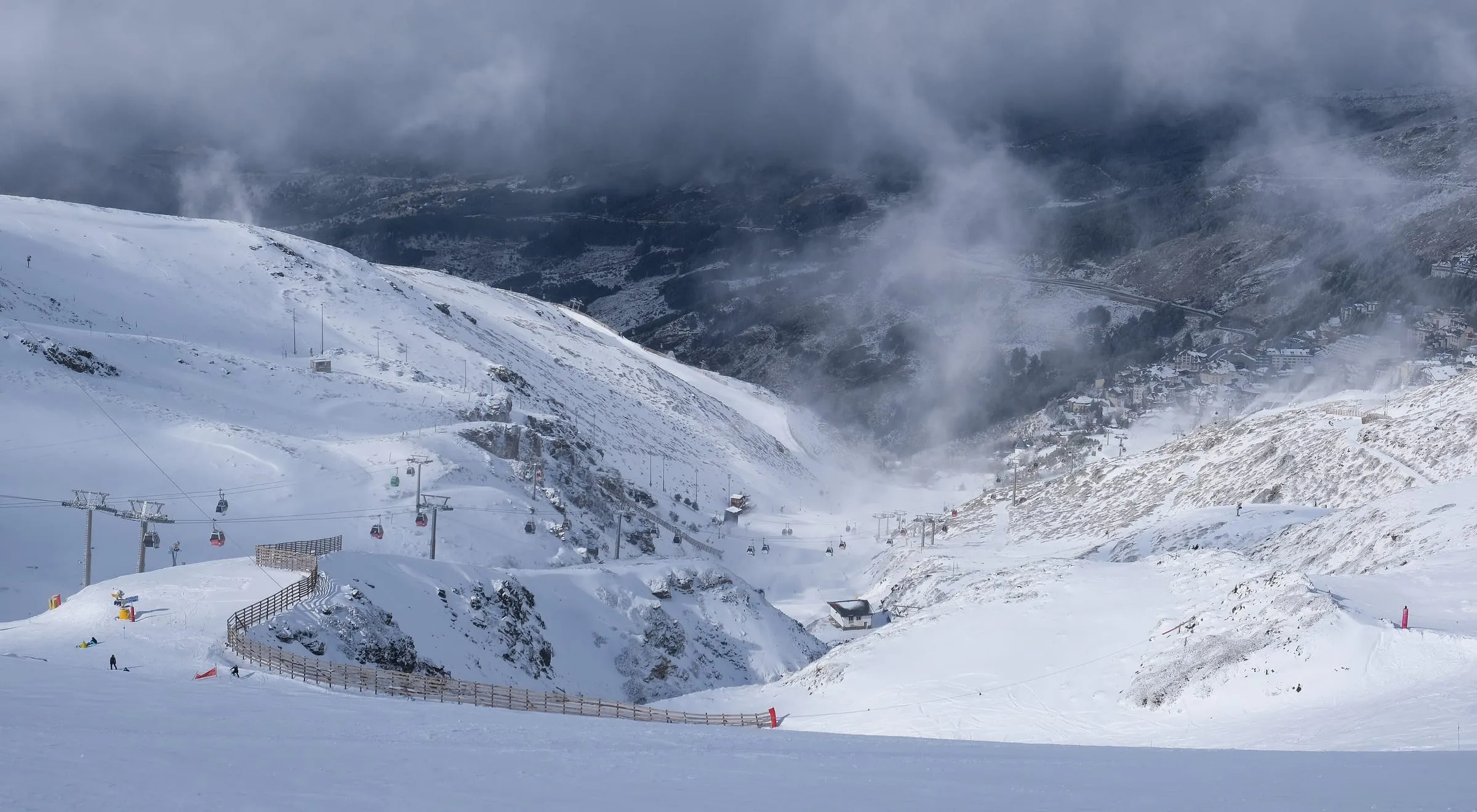 Snowy slopes running down towards Pradollano in Sierra Nevada under passing cloud