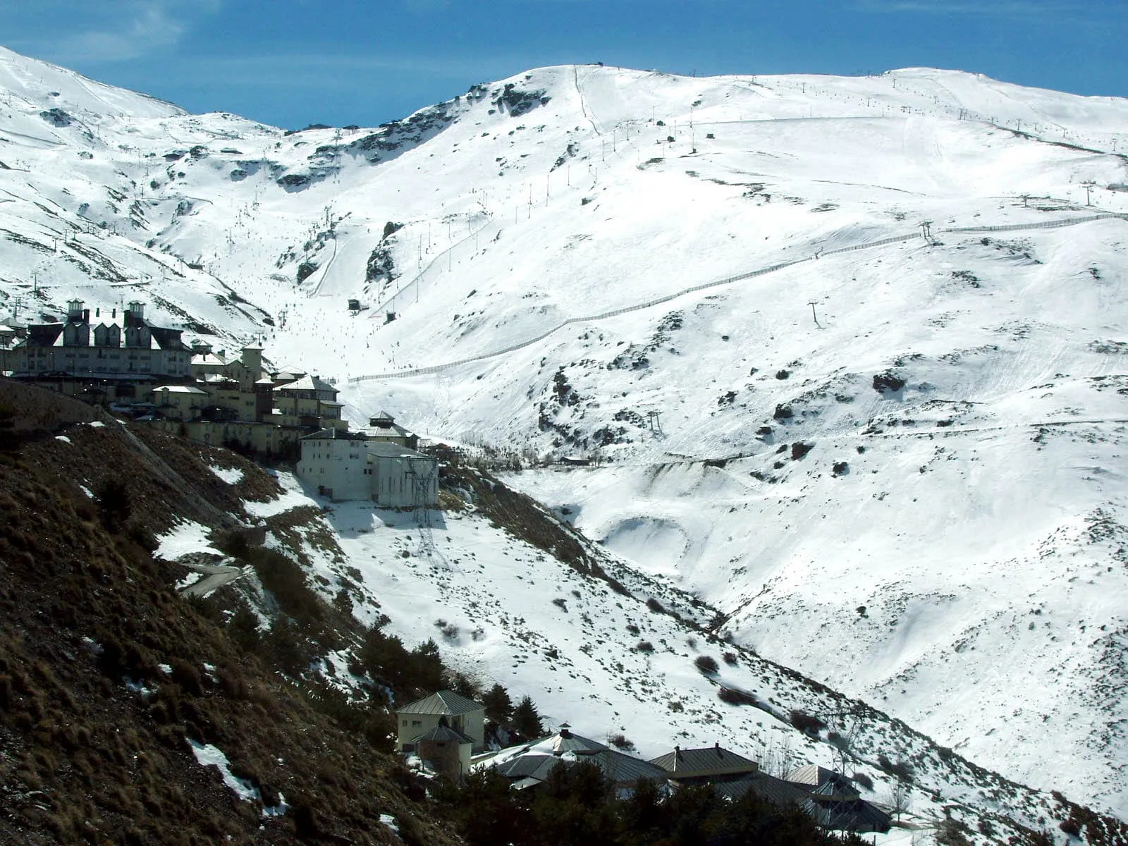 Pradollano, the Sierra Nevada ski village, below snowy slopes on a sunny day