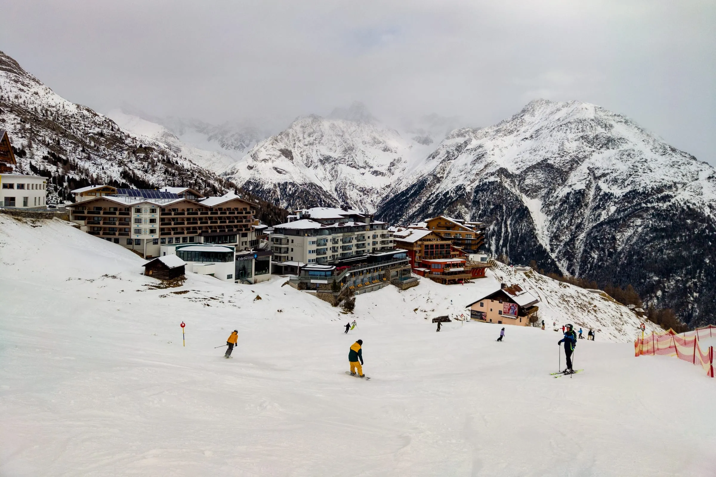 Skiers on the piste beside the hotels of Hochsölden