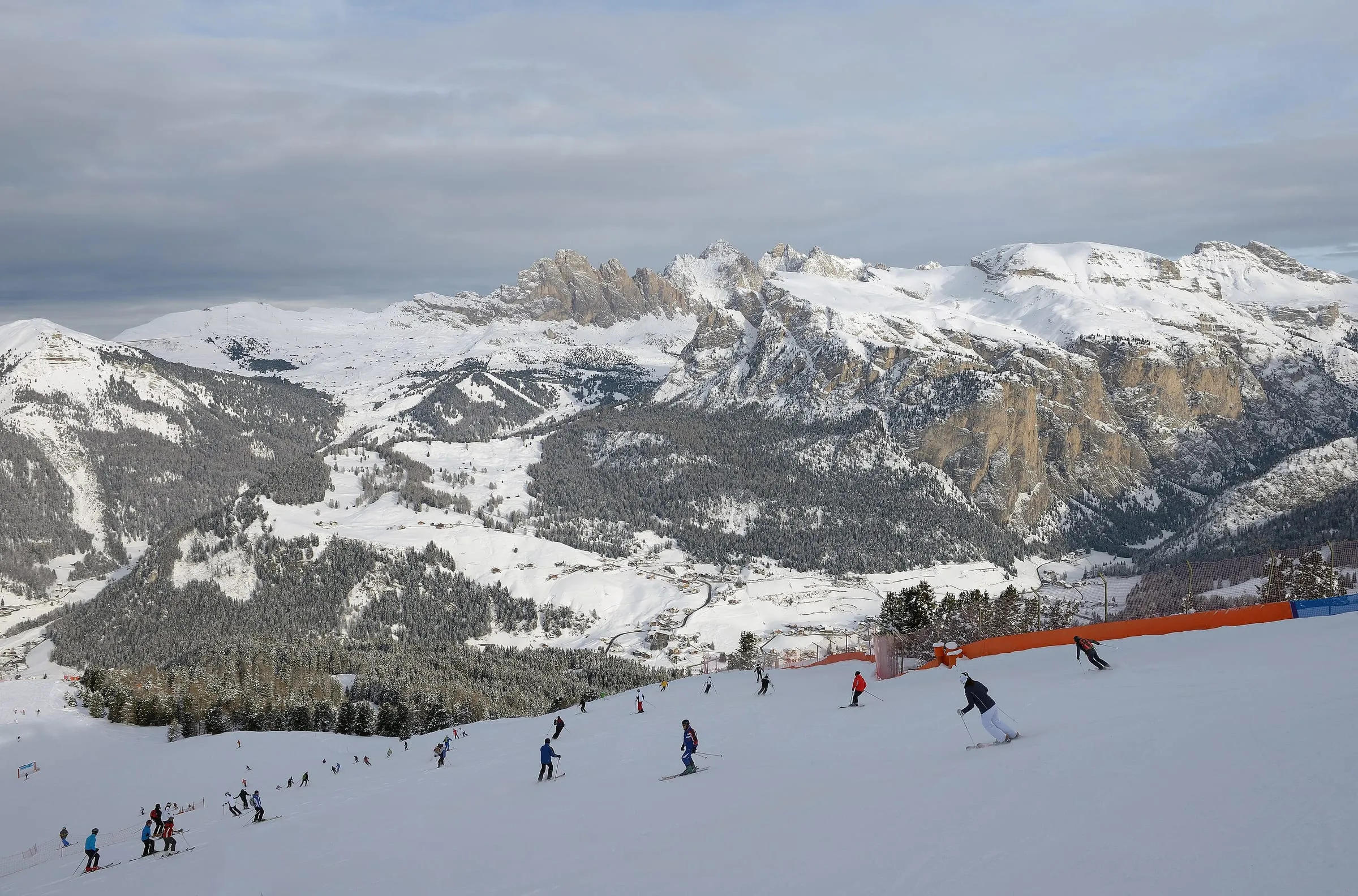 Skiers on the Ciampinoi slopes above Selva in Val Gardena, with Dolomite peaks across the valley