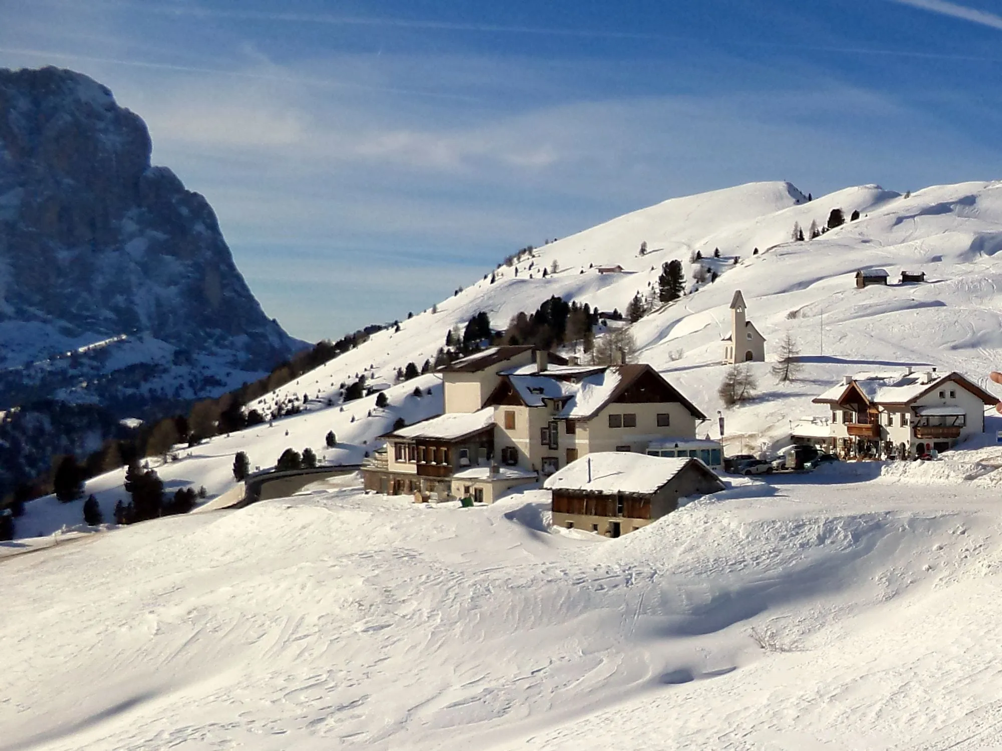 Snowy chalets at the Gardena Pass below the Sassolungo