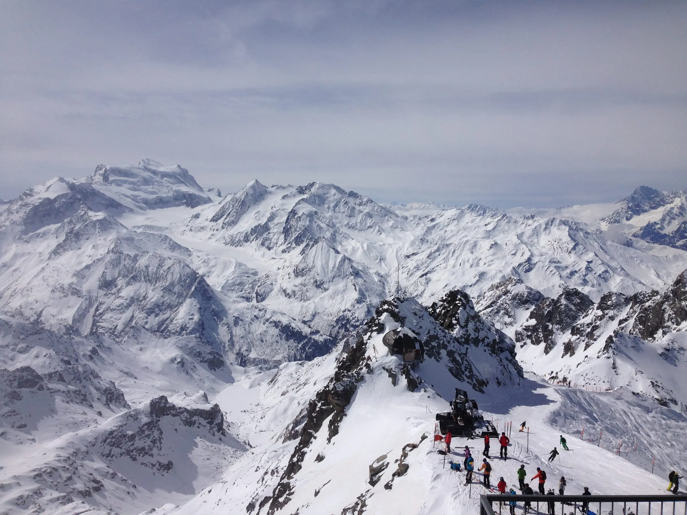Skiers on the snowy summit ridge of Mont-Fort, with the Pennine Alps behind
