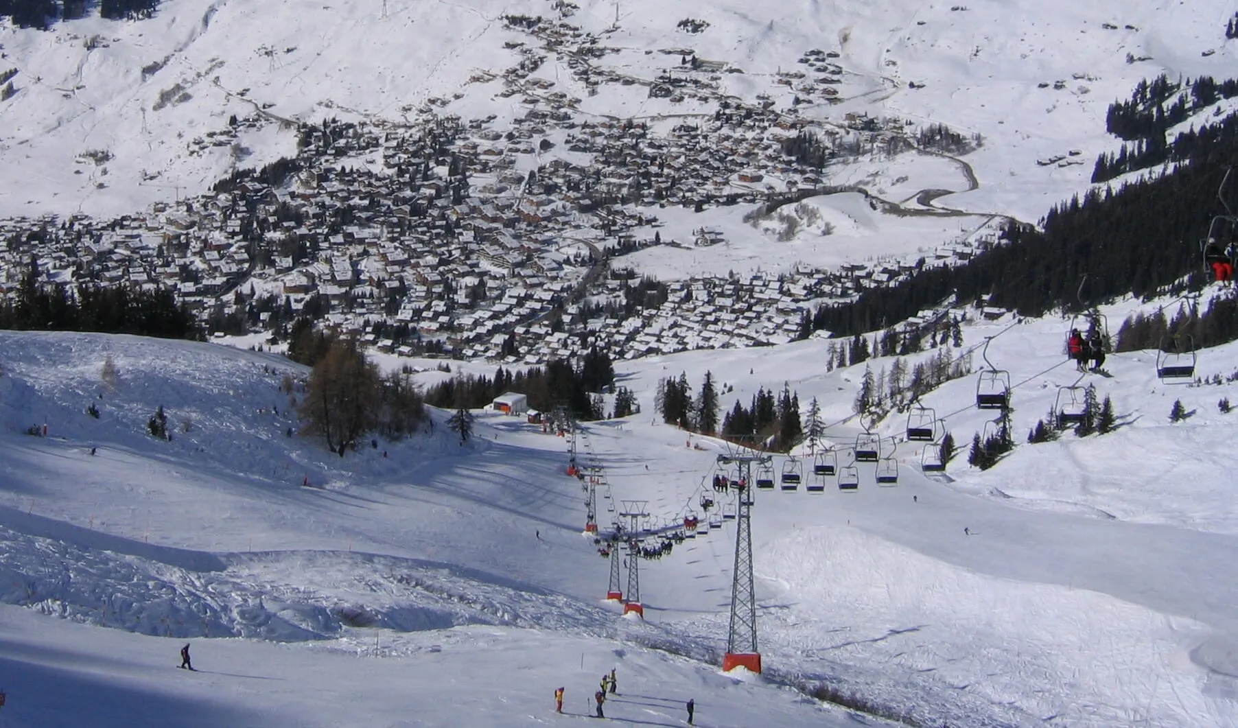 Verbier village spread across the hillside above a chairlift and the lower pistes