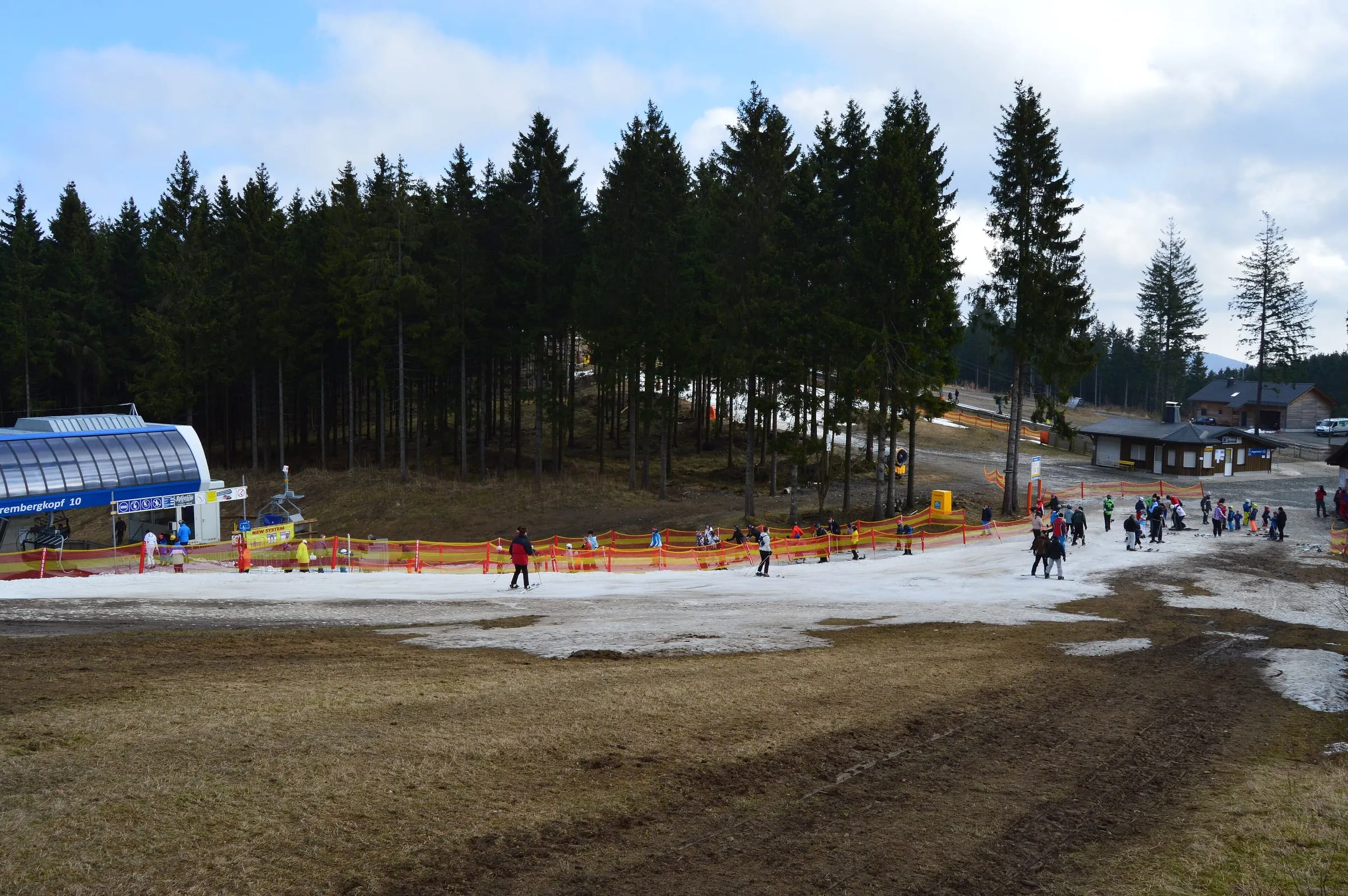 A strip of machine-made snow on green-brown grass at the foot of the Winterberg slopes