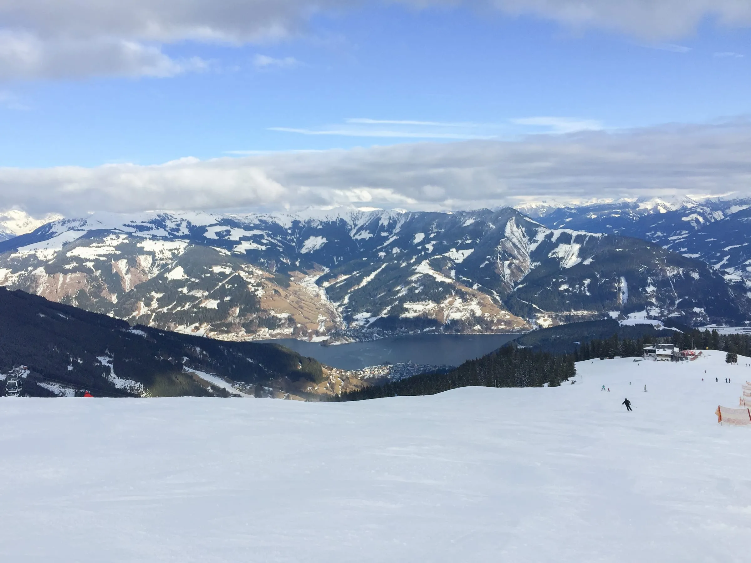 Skiers on a piste on the Schmittenhöhe above Zell am See, with Lake Zell and the mountains behind